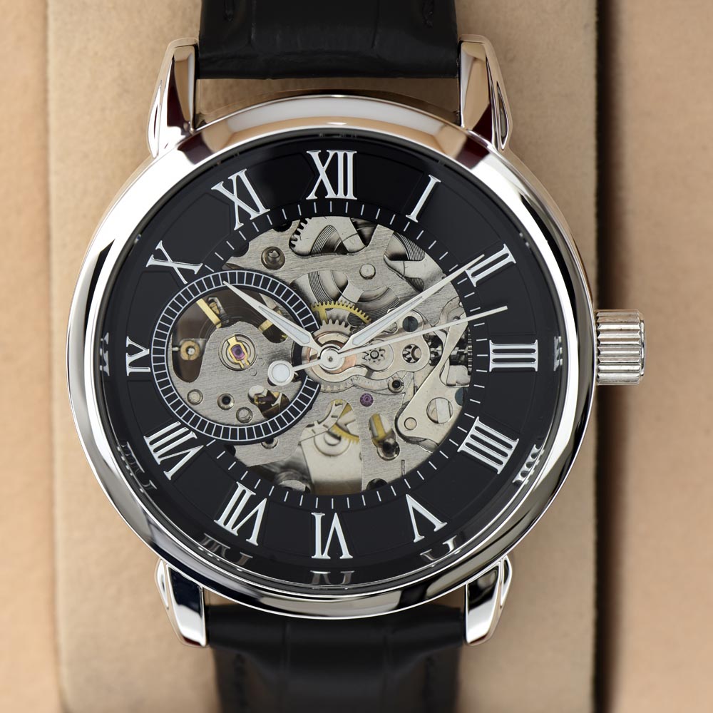 Up-close photograph of a luxury men's openwork mechanical skeleton watch featuring with a polished stainless steel casing, visible moving gears, and a textured black leather strap against a minimalist beige background.