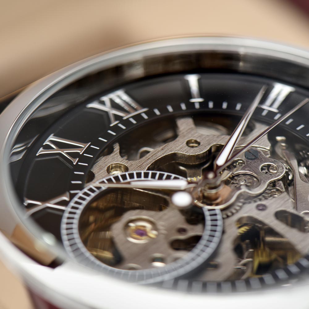 Extreme close-up macro photograph showing the detailed inner workings of a men's openwork skeleton watch, highlighting the interlocking silver and gold mechanical gears, springs, and moving components of automatic movement.