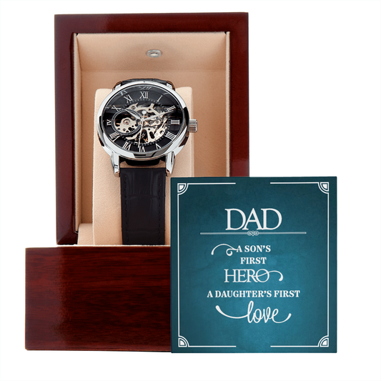 Men's openwork skeleton automatic watch with stainless steel casing and genuine leather band, displayed inside an illuminated luxury mahogany gift box with a soft LED spotlight shining down onto a personalized sentimental message card for a dad.