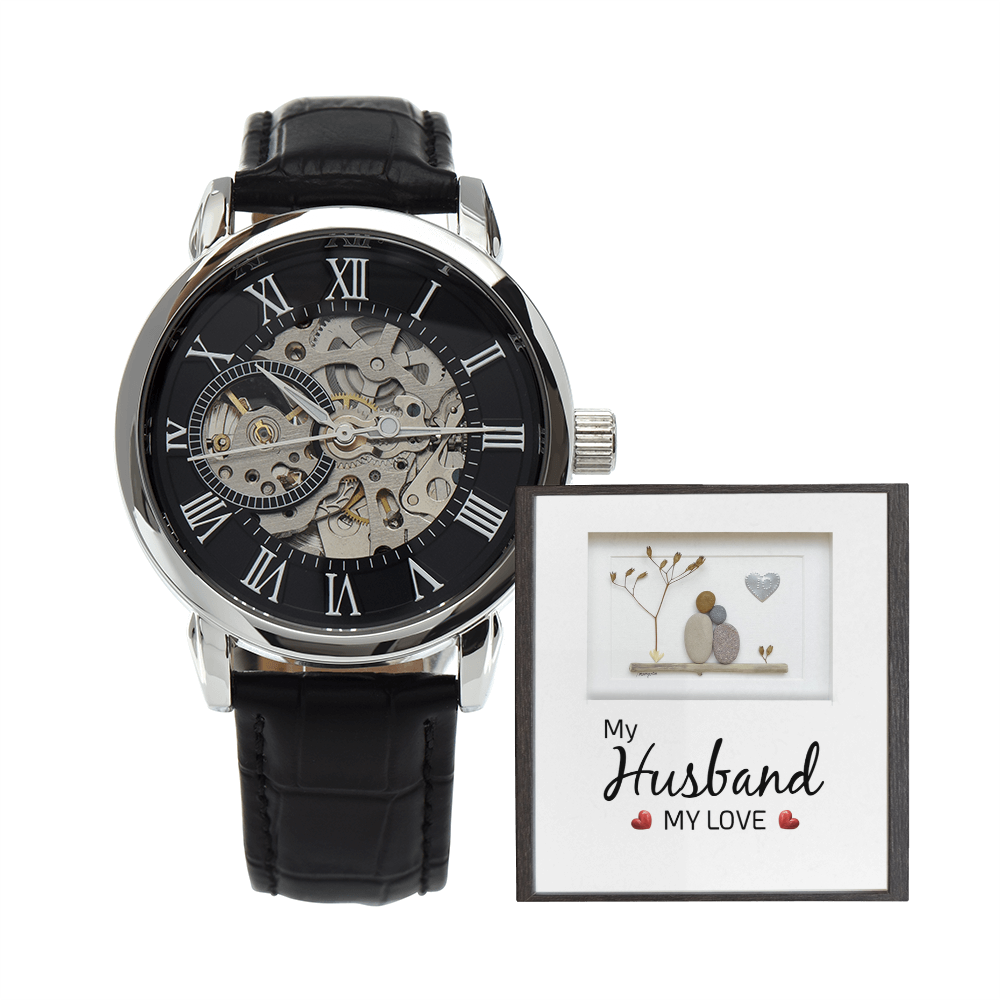 Men's openwork skeleton automatic watch with stainless steel casing and genuine leather band, displayed inside an illuminated luxury mahogany gift box with a soft LED spotlight shining down onto a personalized romantic sentimental message card for a husband.