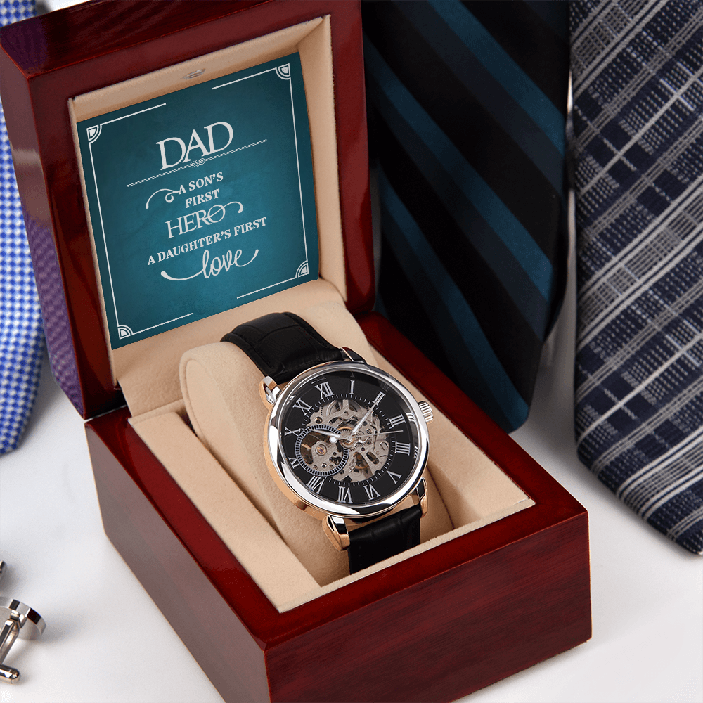 A close-up view of a men's openwork skeleton automatic watch with a black case back, resting inside an open luxury wooden gift box illuminated by an integrated LED light. The background features a neat, organized row of assorted men's ties displayed on a wooden surface.