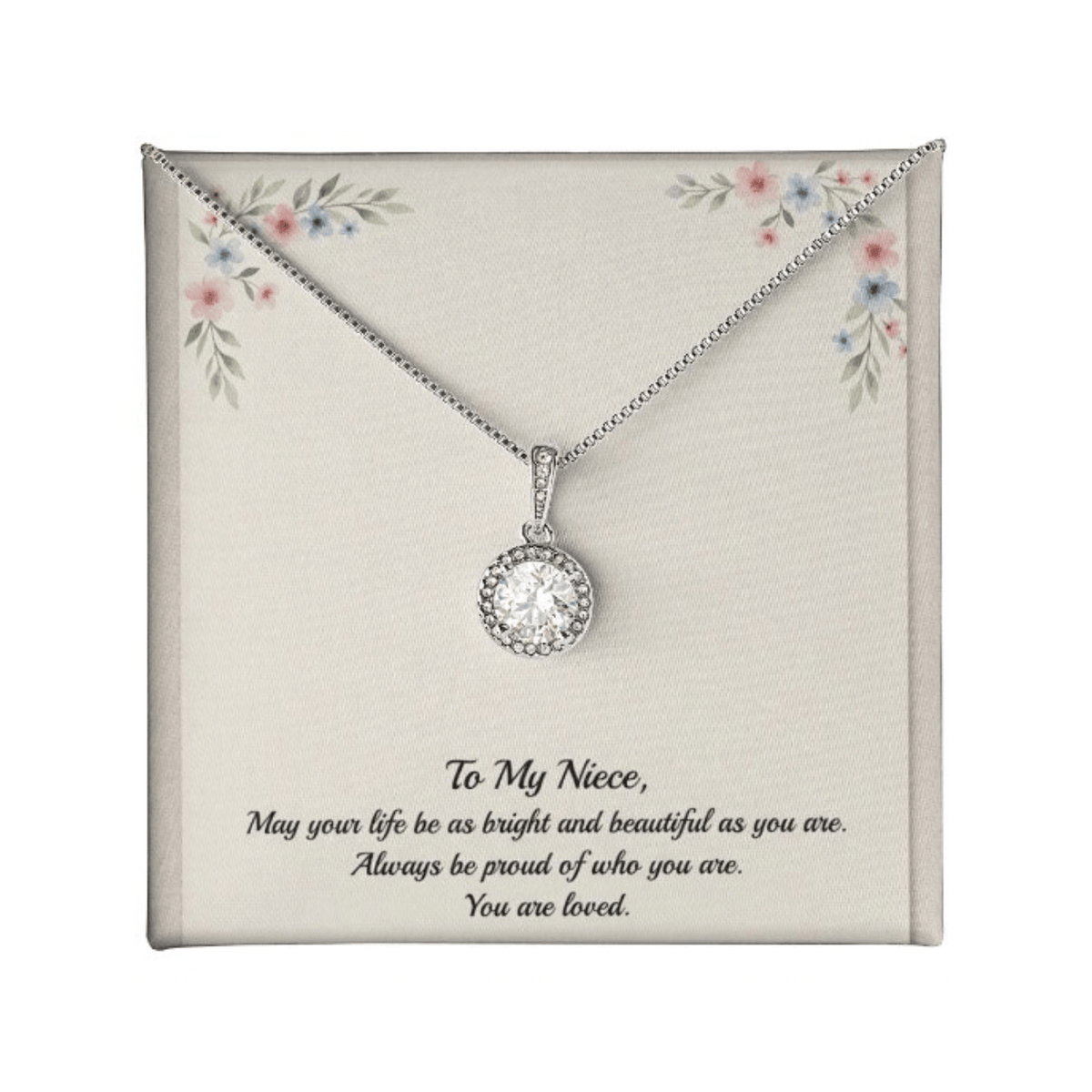 A silver necklace with a round bezel-set clear gemstone pendant, presented on a cream-colored gift card with floral corner details and a sentimental message for a niece.