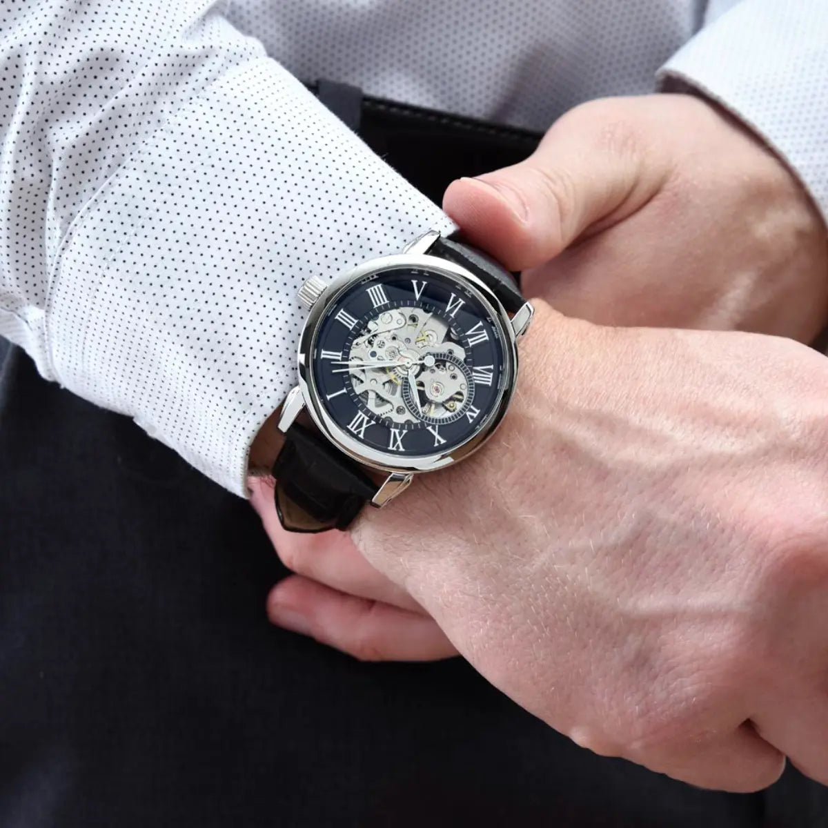 Person wearing a black wristwatch with a white shirt sleeve.