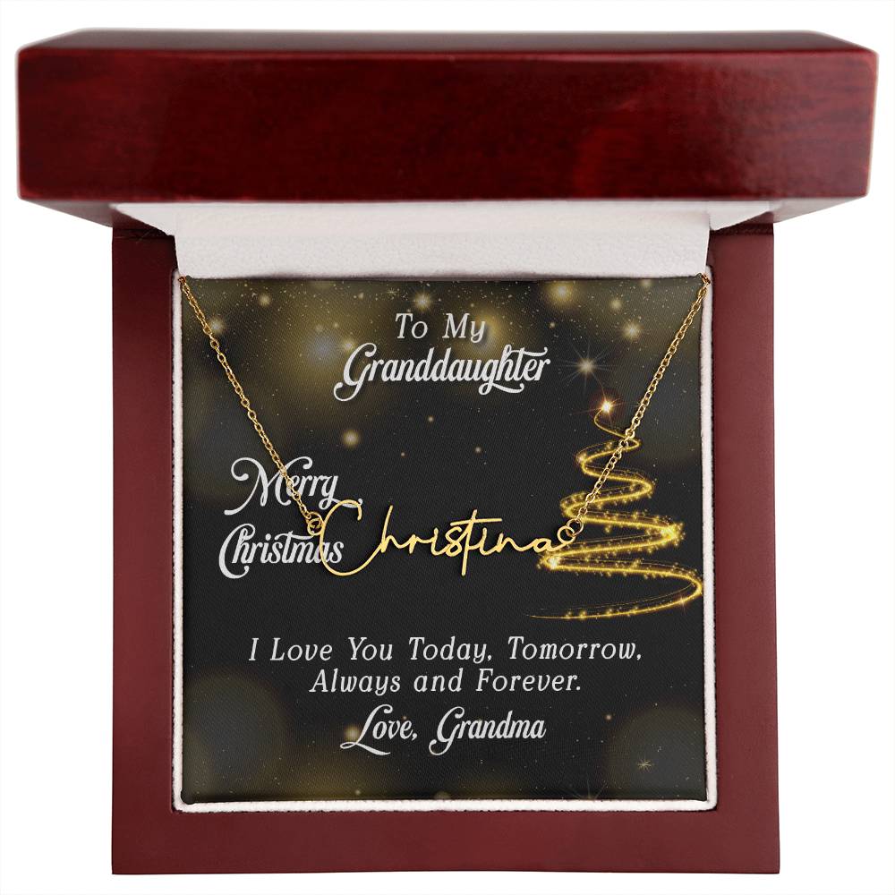Gold personalized signature style name pendant necklace inside a dark wood gift box with a gold glitter Christmas tree jewelry card.