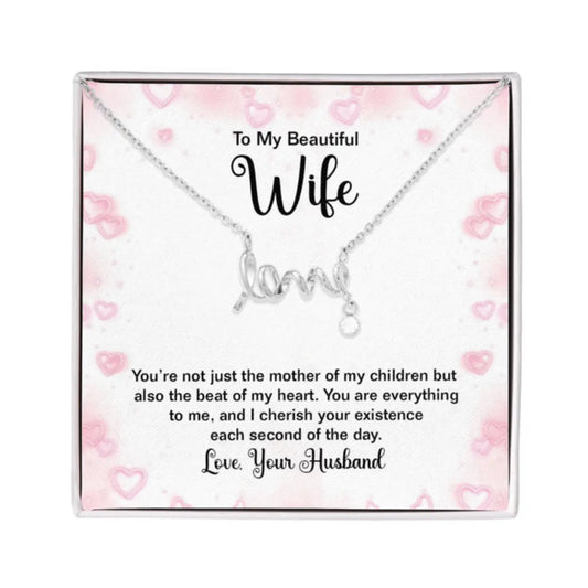 Silver necklace with a cursive 'love' pendant displayed on a pink heart-patterned gift card with a sentimental message for a wife, presented in a clear square box.