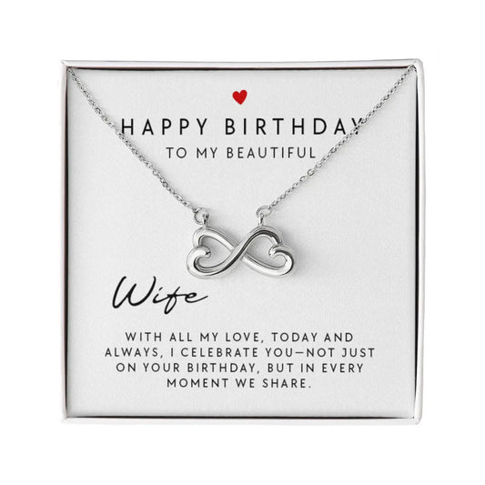 A silver infinity heart necklace presented on a white square gift card that reads 'HAPPY BIRTHDAY TO MY BEAUTIFUL Wife' with a small red heart and sentimental message, photographed on a white background.