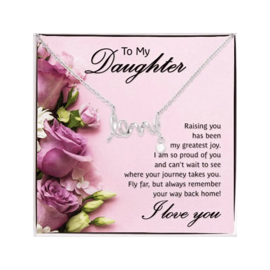 A silver necklace with a cursive 'love' pendant displayed on a pink gift box printed with floral graphics and a sentimental message for a daughter.