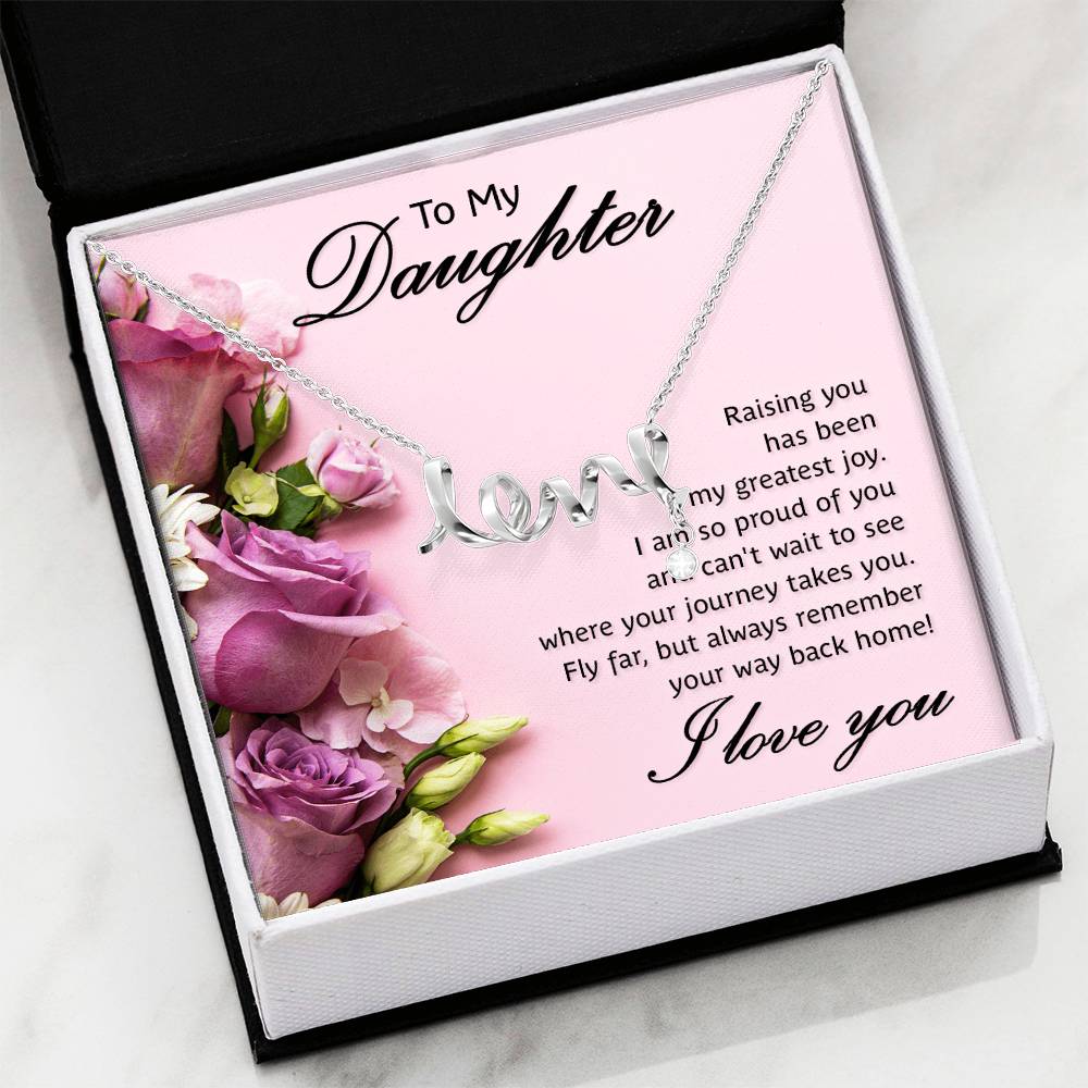 A silver necklace with a cursive 'love' pendant displayed on a pink gift box printed with floral graphics and a sentimental message for a daughter in a black and white gift with a white marble background.