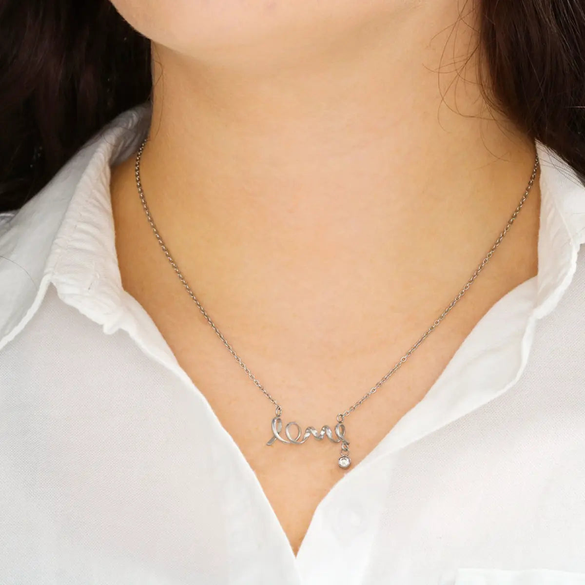 Silver necklace with a pendant worn by a person in a white shirt