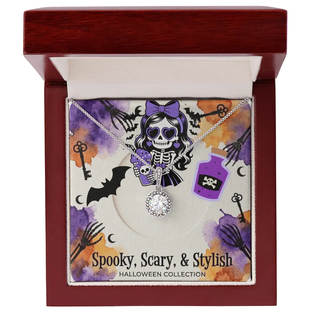A Halloween-themed necklace displayed inside an open dark red wooden gift box. The necklace has a silver-tone chain and a central round clear stone pendant, with smaller purple and black skull-and-skeleton charms.