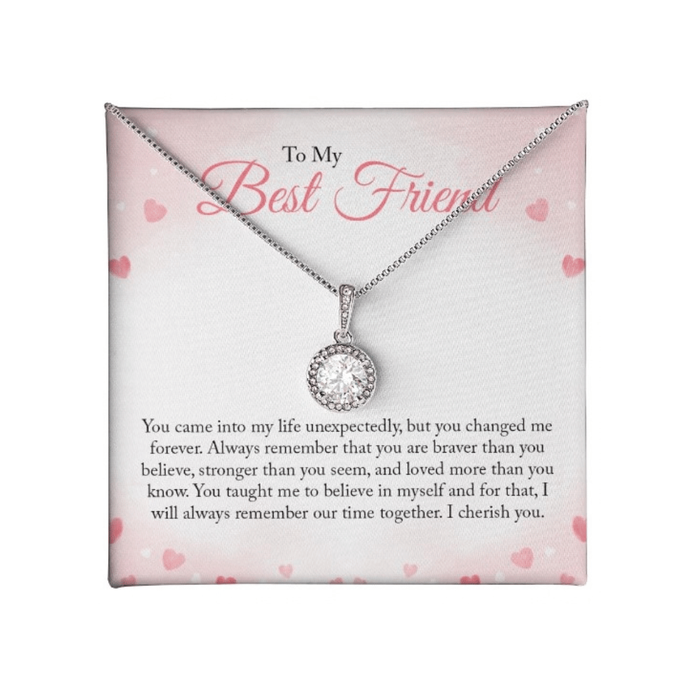 A round-cut cubic zirconia pendant necklace in white gold over a personalized 'To My Best Friend' sentimental message card with pink hearts.